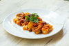 Squid pieces in american sauce being served in a dish